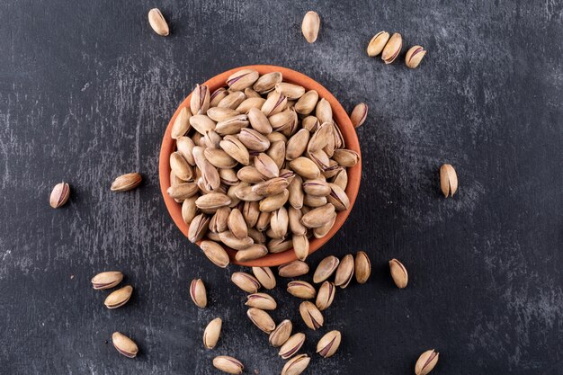 Top view pistachios in a bowl on gray texture