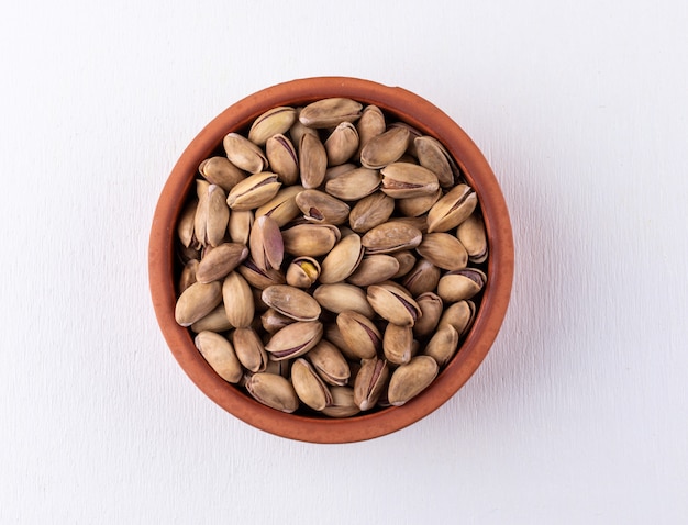 Top view pistachios in a bowl on white  horizontal