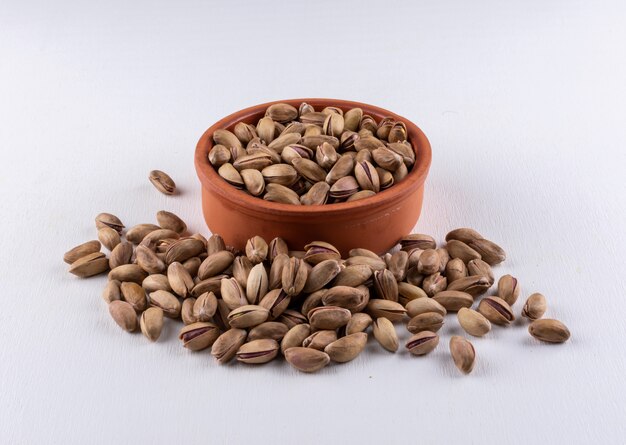 Top view pistachios in a bowl on white