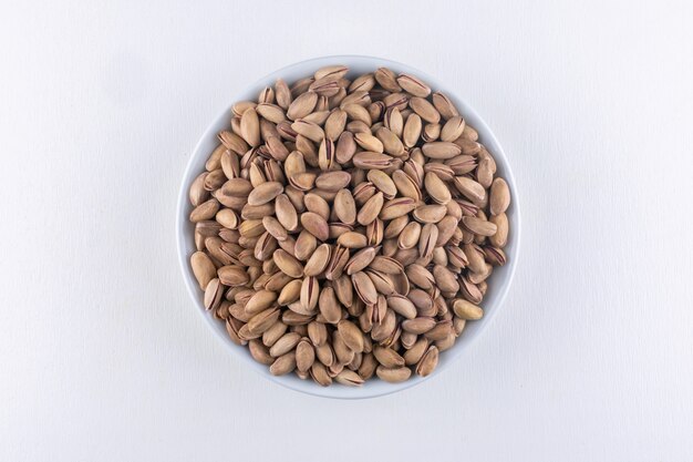 Top view pistachios in a bowl on white