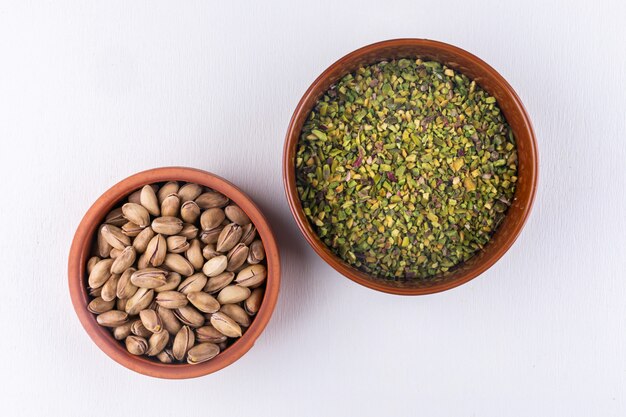 Free photo top view pistachios in bowls on white horizontal