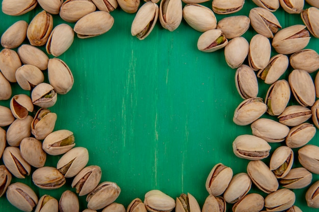 Free photo top view of pistachios on a green surface