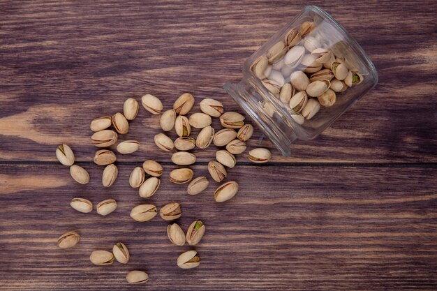 Top view of pistachios in a jar on a wooden surface