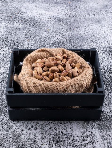 Free photo top view pistachios in sack in box on gray  horizontal