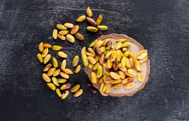 Top view pistachios on a stump on dark texture  horizontal 1