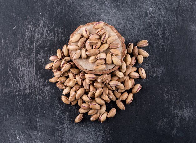 Top view pistachios on a stump on gray texture  horizontal