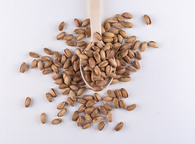 Top view pistachios in wooden spoon on white 