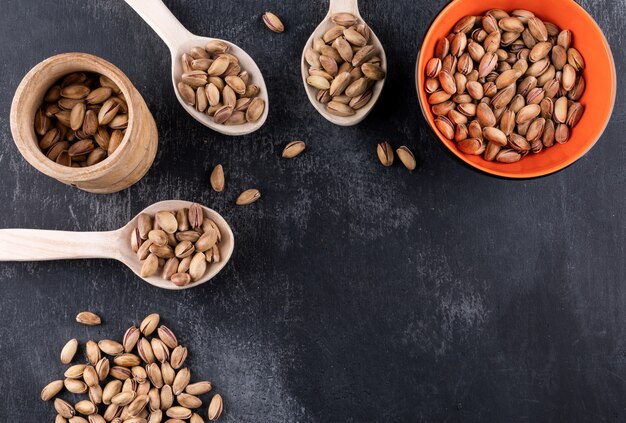 Top view pistachioswith copy space in bowl and wooden spoons on gray texture  horizontal