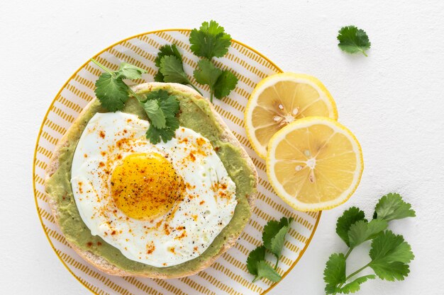 Top view pita with avocado spread and fried egg  with lemon slices