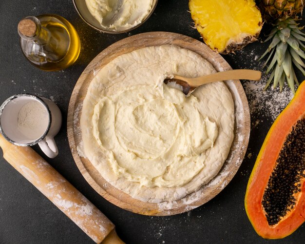 Top view of pizza dough in bowl with pineapple and papaya