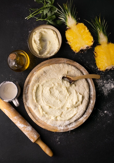 Top view of pizza dough in bowl with pineapple