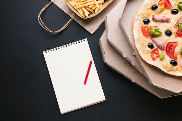 Top view pizza and fries with notebook