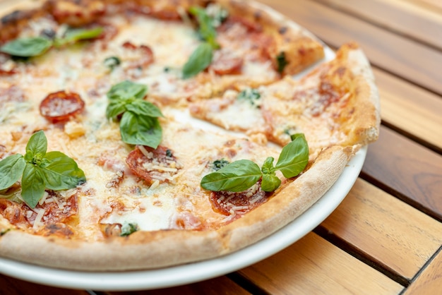 Top view of pizza with basil on wooden table