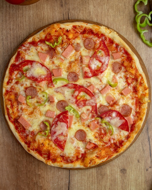 Top view of pizza with sausages tomato bell pepper and cheese