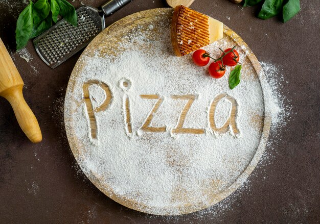 Вид сверху пиццы, написанной в муке с пармезаном и помидорами