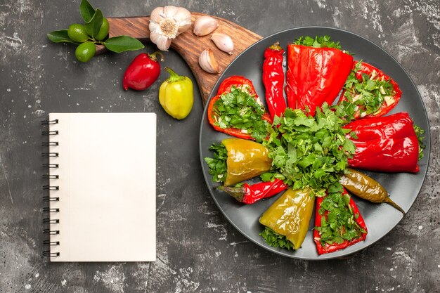 Top view plate of peppers plate of peppers garlic peppers on the board white notebook