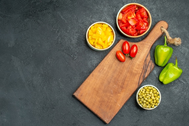 Free photo top view of plate stand with tomatoes on it and other vegetables on side with free place for text on dark grey background