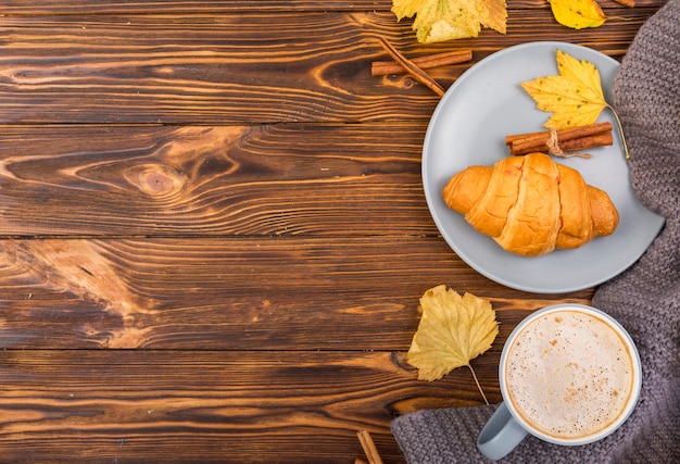 Top view plate with croissant and coffee copy space