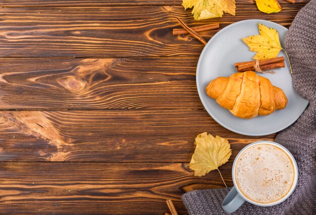 Top view plate with croissant and coffee copy space