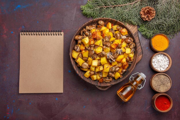 Top view plate with food plate with fried mushrooms and potatoes colorful spices oil and notebook next to the branches with cones