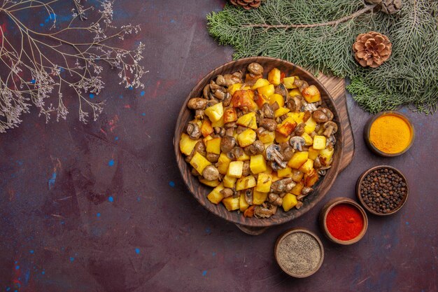 Top view plate with food plate with fried potatoes and mushrooms different spices next to the fir branches with cones