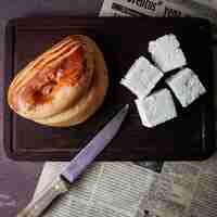 Free photo top view pogaca with cheese and knife and old newspaper in cutting board