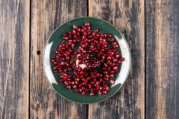 Top view pomegranate in plate on wooden surface