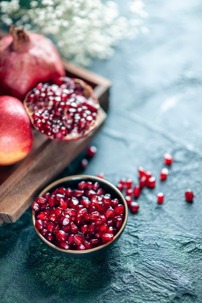 Top view pomegranate seeds bowl pomegranates on wood serving board on table