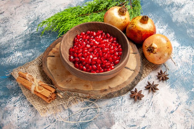 Top view pomegranate seeds in bowl on tree wood board cinnamon anise seeds pomegranates on blue-white background