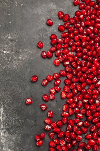 Top view of pomegranate seeds on dark surface