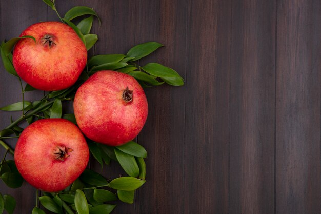 Top view of pomegranate with leaf branch on wooden surface