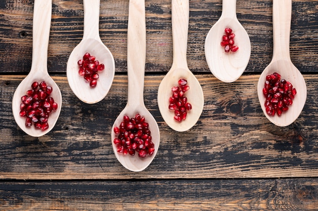 Top view pomegranate in wooden spoons on wood table