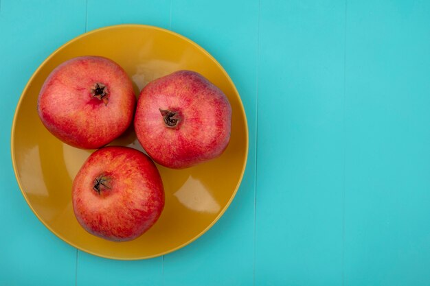 Top view of pomegranates in plate on blue surface