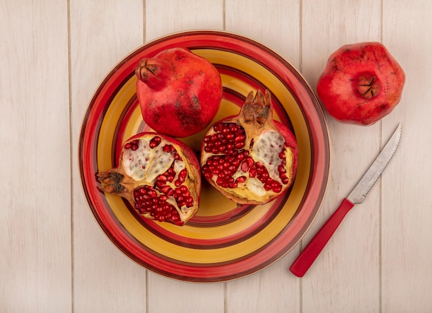 Free photo top view pomegranates on a red and yellow plate with a knife