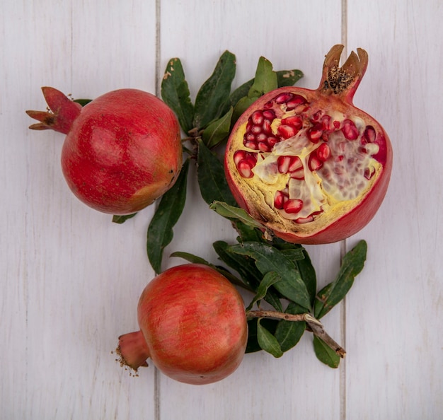 Top view pomegranates with branches of leaves on a white background