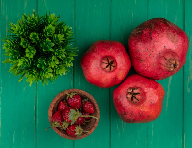 Top view pomegranates with strawberries on green wall