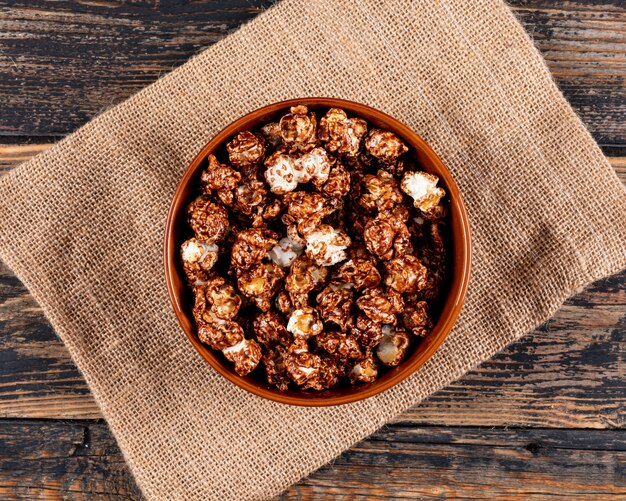 Top view of popcorn in bowl and sackcloth on dark wooden  horizontal