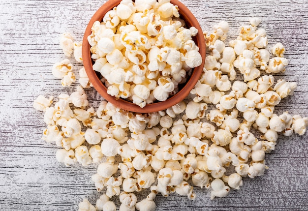 Foto gratuita vista superiore di popcorn in ciotola sull'orizzontale di legno bianco