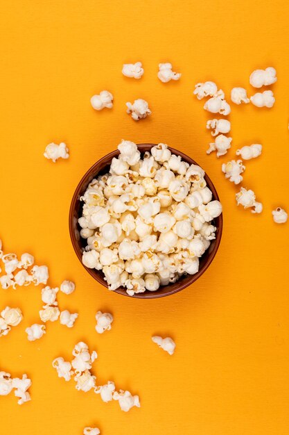Top view of popcorn in bowl on yellow  vertical