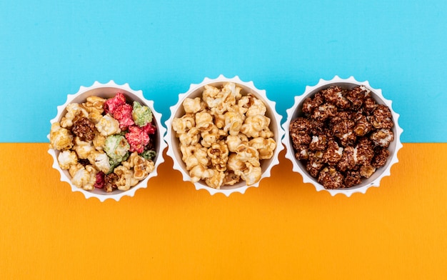 Top view of popcorn in bowls on blue and yellow  horizontal