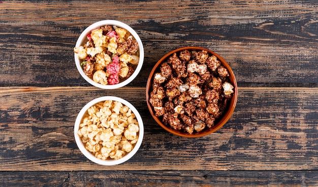 Top view of popcorn in bowls on dark wooden  horizontal