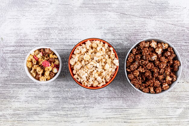 Top view of popcorn in bowls on white wooden  horizontal