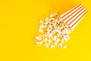 Free photo a top view popcorn package salted tasty spread all over the yellow background