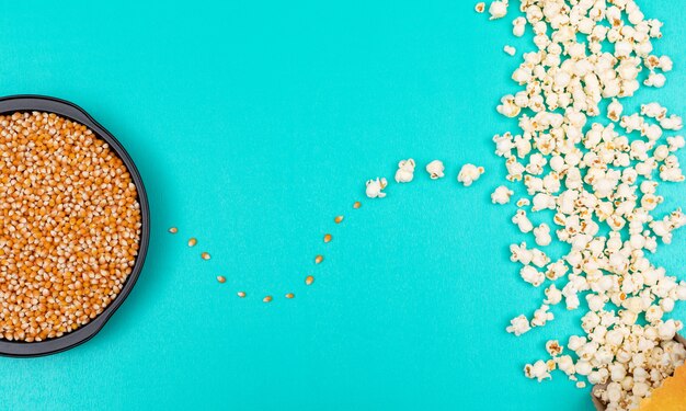 Top view of popcorn seeds in black metal pan on left and prepared on right on blue background horizontal