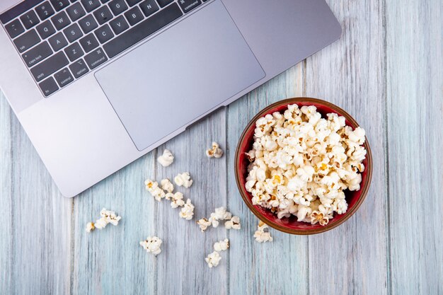 Top view of popcorn on a wooden bowl on grey wooden surface