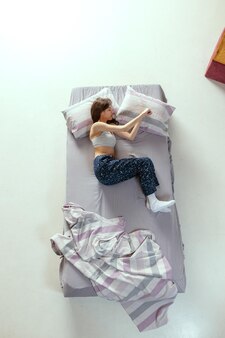편안한 휴식 낮잠의 개념 침대에서 자는 젊은 여성의 상위 뷰 초상화
