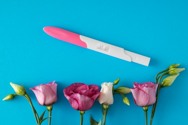 Free photo top view positive pregnancy test and flowers