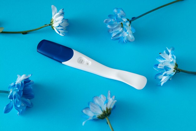 Top view positive pregnancy test and flowers