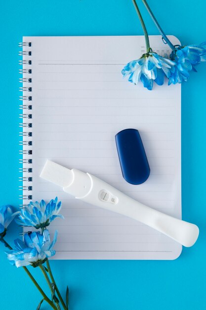 Top view positive pregnancy test and flowers