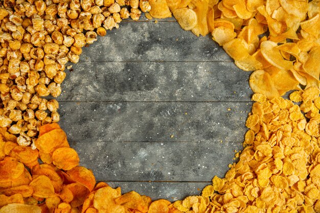 Вид сверху картофельные чипсы кукурузные хлопья и сладкий попкорн с копией пространства